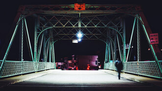 Silueta de un hombre caminando por un puente en una noche solitaria