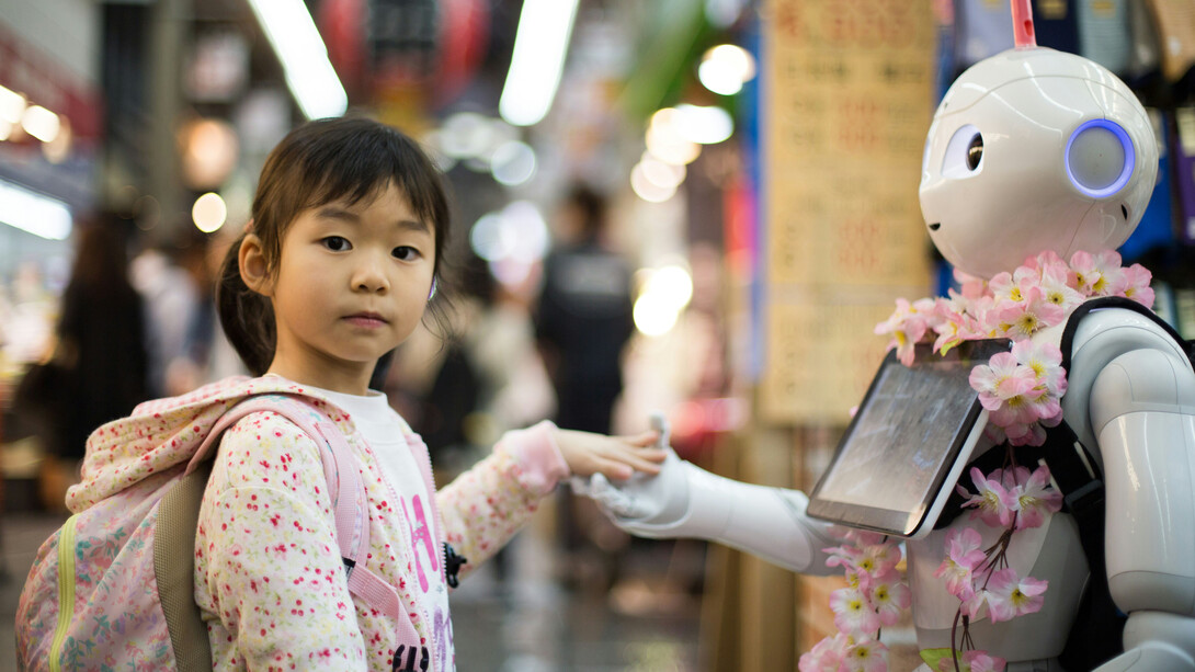 A young girl holding hands with a robot