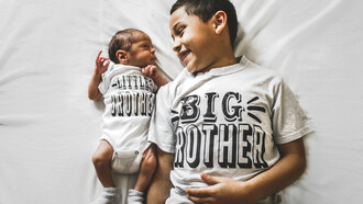 Newborn baby beside his older brother in a photograph