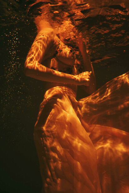 A surreal underwater scene of a beautiful woman in a brassiere and sheer skirt, evoking reflection and the abstraction of the human profile