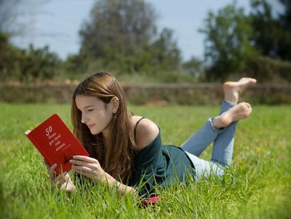 Una chica leyendo un libro en el campo