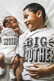 Newborn baby beside his older brother in a photograph