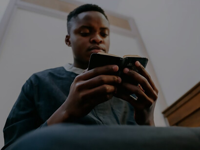 A man dressed in a black soutane, deep in contemplation, immersed in reading a Bible