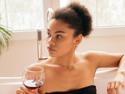 A woman with a glass of wine inside a bathtub