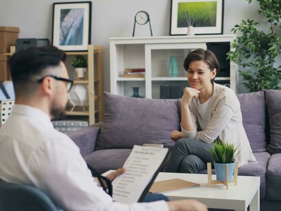 A man and a woman sit together on a couch, engaged in conversation