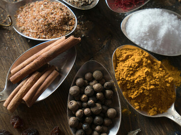 An assortment of spices and herbs arranged on spoons, symbolizing the Caucasus tradition of herbal remedies and natural medicine