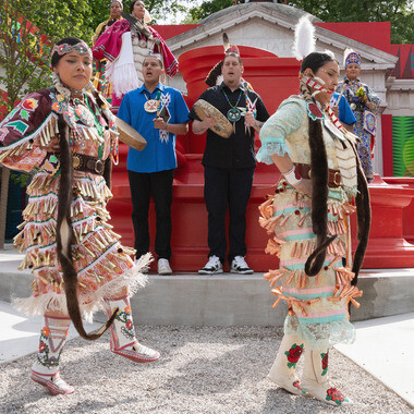 Adriano Pedrosa assume a direção da 60ª Bienal de Veneza, focando em diversidade cultural e inclusão com a exposição "foreigners everywhere". Membros dos Oklahoma Fancy Dancers e Colorado Inter-Tribal Dancers ativando o pátio do Pavilhão dos EUA para a exposição de Jeffrey Gibson. Bienal de Arte 2024. Fotografia de Federica Carlet