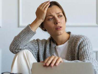 A distressed woman sitting on a chair, struggling with financial issues