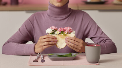 Adult seen from the front holding a sandwich filled with flowers