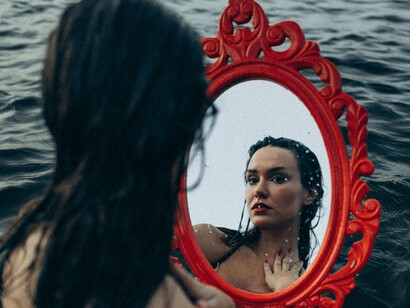Mulher se observa no espelho. Um dos maiores desafios é equilibrar a adaptação à nova cultura com a preservação da própria essência. 