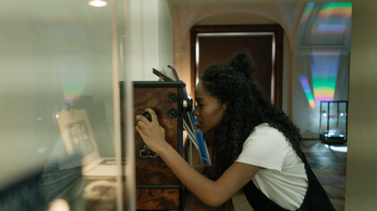 Jovem olha através de caleidoscópio antigo e pensa sobre as transformações do tempo