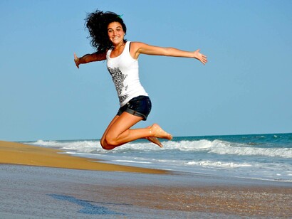 A woman jumping on the beach brimming with happiness