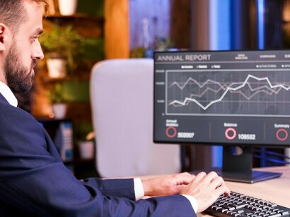 The manager evaluates financial graphs and stock market trends on the monitor, strategizing for options trading