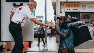 A humanitarian worker providing food assistance to a homeless man, representing efforts to uphold the right to food
