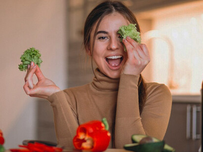 A woman preparing a healthy plant-based meal in the kitchen, featuring fresh vegetables and fruits to support vegan nutrition