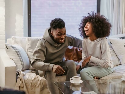 A relaxed couple smiles while spending quality time together at home, enjoying a cozy and intimate setting
