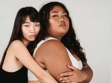 Asian homosexual couple embracing and hugging each other against a gray background