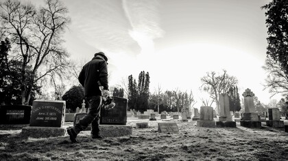 A person walking in a cemetery where the dead are buried but remembered 