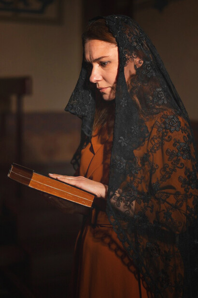 A woman engages in a religious pilgrimage, with a serene expression, near the church