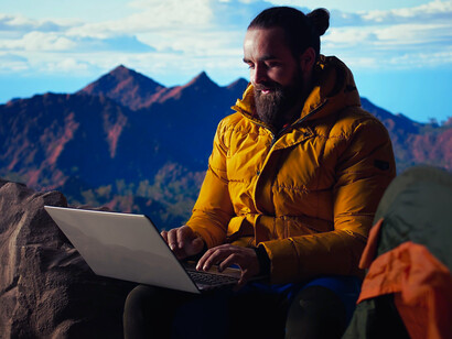 A remote worker completing work from a mountain summit, symbolising the shift from office spaces to open landscapes