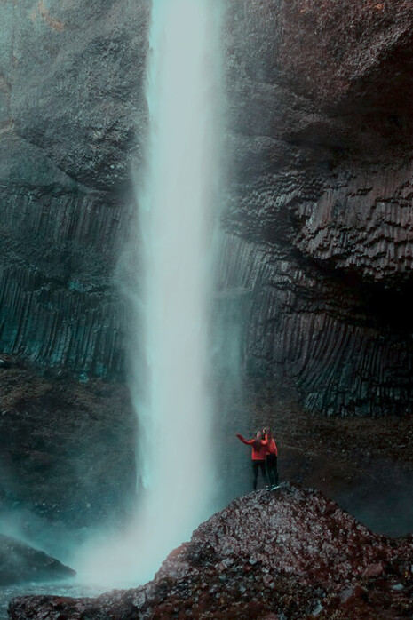 Two people standing by a waterfall