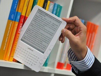 Un libro electrónico en una estantería con otros libros de papel