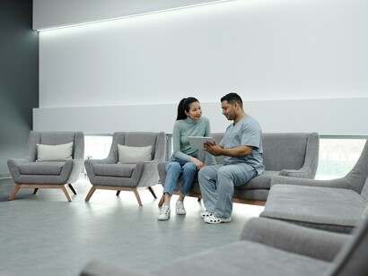 A conversation between a medic and patient in an empty waiting area, symbolising how access to healthcare often begins with waiting