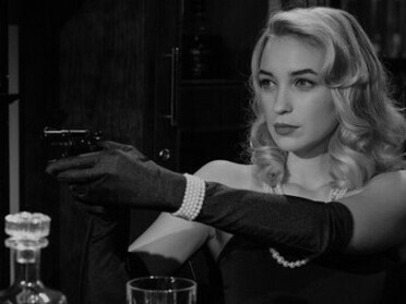 Mulher aponta uma arma para o outro lado da mesa