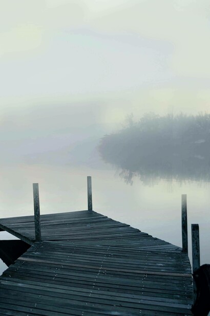 Ponticello in legno su un lago mentre albeggia: "Il credente, il cristiano vive già di un altro mondo, è già mezzo pesce e mezzo volatile, possiede delle branchie interne invisibili che gli permettono di nuotare già nei mari superni, celesti"