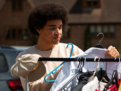 Browsing through gently used clothes at a local yard sale, this shopper embraces a minimalist mindset, focusing on long-lasting items over disposable trends