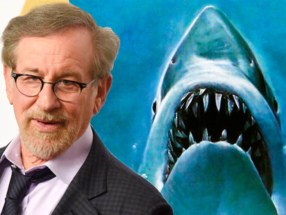 Steven Spielberg e o cartaz do filme "Tubarão". No próximo verão, comemoraremos os 50 anos do primeiro grande filme-evento de verão americano, “Tubarão”