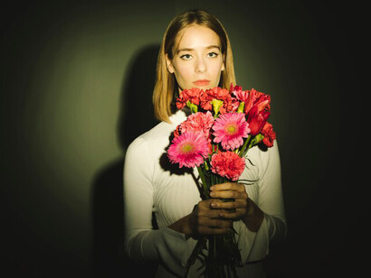 A reflective woman cradling a bouquet of flowers