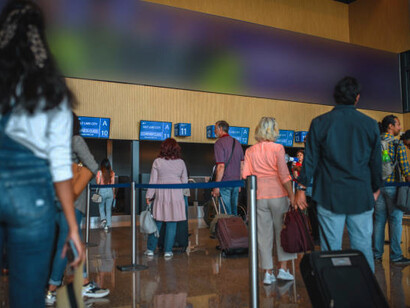 People waiting in line at airport check-in, passing through border security, visa control, and customs