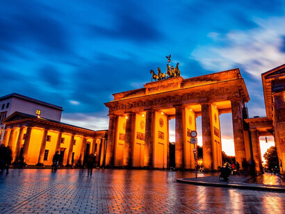 As the sun sets behind the Brandenburg Gate in Berlin, Germany, its majestic form casts long shadows, echoing the complex history of East and West Germany and the hope for reunification