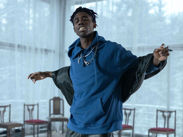 A performer rapping alone in a minimal space, reflecting how shared trends blur once-distinct identities
