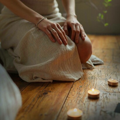 Una persona inginocchiata davanti a piccole candele accese