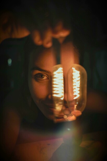 O brilho da lâmpada ilumina parcialmente o rosto feminino, criando uma cena de tensão e revelação. Na música, vir de dia é também exigir verdade e responsabilidade