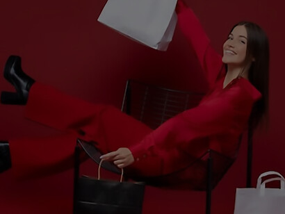 In a full-shot frame, a radiant woman exudes happiness as she proudly holds an array of vibrant shopping bags