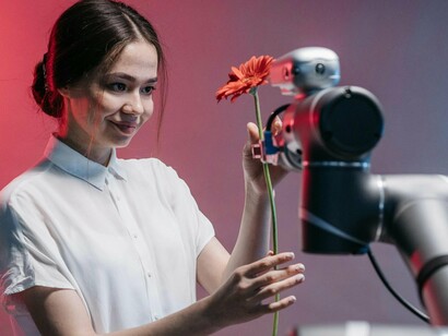 Mulher recebe flor de robô. A estimulação cerebral ocorre por meio de jogos cognitivos personalizados, que auxiliam na prevenção de doenças neurodegenerativas, como o Alzheimer. No campo da educação, ferramentas de aprendizado baseadas em inteligência artificial sugerem conteúdos adaptados às necessidades dos estudantes, facilitando o processo de ensino e aprendizagem