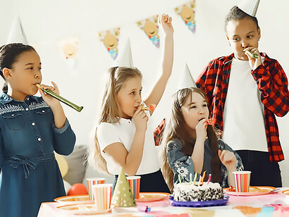 The child exuberantly celebrates her birthday surrounded by friends, creating an atmosphere of pure joy and happiness