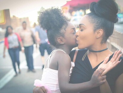 A black mother and daughter sharing an intimate moment on a crowded street and expressing their love and gratitude for one another