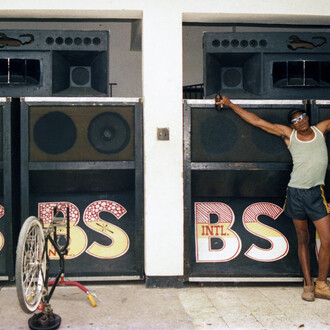 Beth Lesser, Papa Screw, selector for the Black scorpio sound system, in front of the speaker boxes in the Scorpio headquarters, Drewsland, Kingston, Jamaica (detail), 1985. Courtesy of MCA Chicago