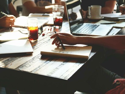 A meeting of young minds on a coffee table with open laptops are discussing the progress they've made
