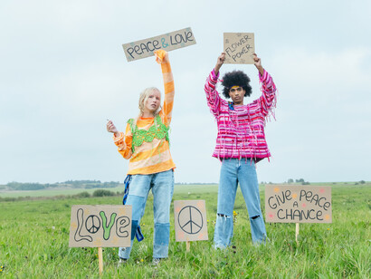 Peace and love and flower power are the signs a man and a woman hold up to the sky