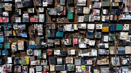 Aerial view of an overcrowded township in South Africa, where homes stretch as far as the eye can see, highlighting the complex history of land distribution and urban planning while illustrating the stark reality of inadequate living conditions
