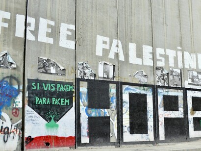 A message on the separation wall demanding freedom, reflecting how global cooperation is shaped by acts of defiance such as social media activism during conflict