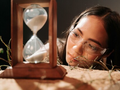A woman's fascination with time sifting down the hourglass aparatus