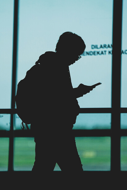 Surabaya, East Java, Indonesia, a silhouette of a person with a backpack walks while looking at their phone