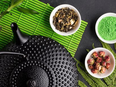 Herbal tea alongside its dried ingredients displayed on a green placemat