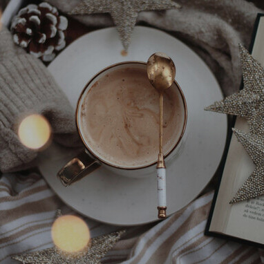 A cup of hot chocolate resting on a white wool sweater, evoking warmth and comfort while symbolizing the link between chocolate, serotonin, and happiness